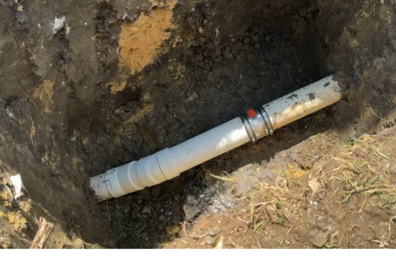Exposed section of PVC sewer pipe with a repair coupling in a dug-out pit